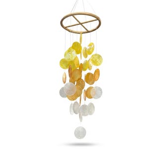 May include: A decorative wind chime with a wooden ring and strings of iridescent, circular shells. The shells transition in colour from yellow to orange and white, creating a gradient effect. The wind chime is suspended against a white background.