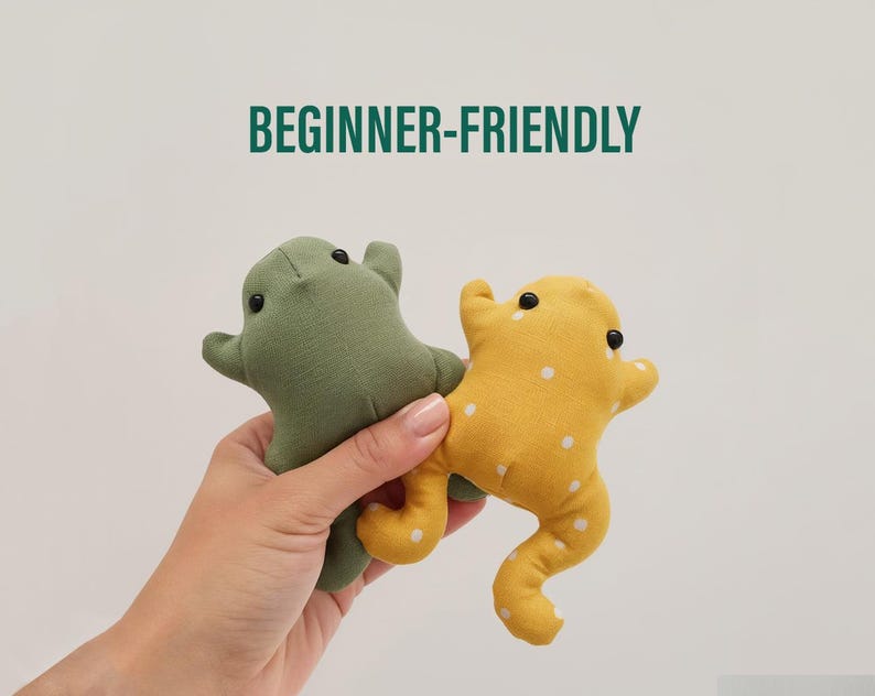 Peut inclure: Deux peluches en forme de grenouille faites &agrave; la main. L'une est vert olive, l'autre est jaune &agrave; pois blancs. Les deux ont des yeux noirs en forme de bouton. Le texte "BEGINNER-FRIENDLY" est au-dessus des grenouilles.
