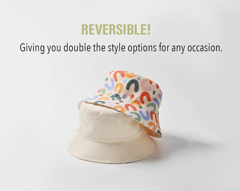 May include: A reversible bucket hat with a colorful abstract pattern on one side and a solid cream color on the other side. The hat is made of a lightweight fabric and has a wide brim.