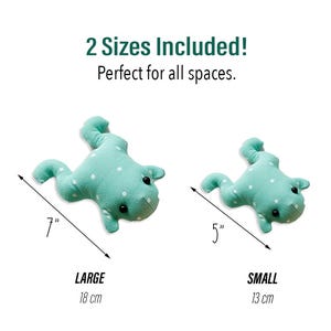 Peut inclure: Deux jouets en forme de grenouille en peluche de diff&eacute;rentes tailles. La grande grenouille mesure 18 cm de long et la petite grenouille mesure 13 cm de long. Les deux grenouilles sont vert clair avec des pois blancs. Le texte "2 Sizes Included!" est en haut.