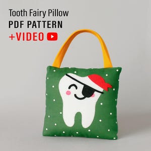 Puede incluir: Una almohada verde para el hada de los dientes con un diente blanco que lleva un parche en el ojo y un sombrero rojo. La almohada tiene un asa amarilla y lunares blancos. El texto en la almohada dice "Tooth Fairy Pillow PDF PATTERN + VIDEO".