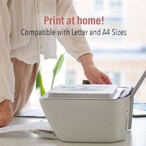 May include: A white printer with a document tray and a paper feed slot. The printer is on a white desk with a laptop computer to the right. The text "Print at home! Compatible with Letter and A4 Sizes" is displayed above the printer.