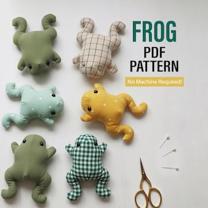 May include: Six plush frog toys in various fabrics including solid olive green, light blue with white dots, yellow with white dots, beige plaid, and green gingham. Text reads FROG PDF PATTERN No Machine Required. Includes gold scissors and three pins.