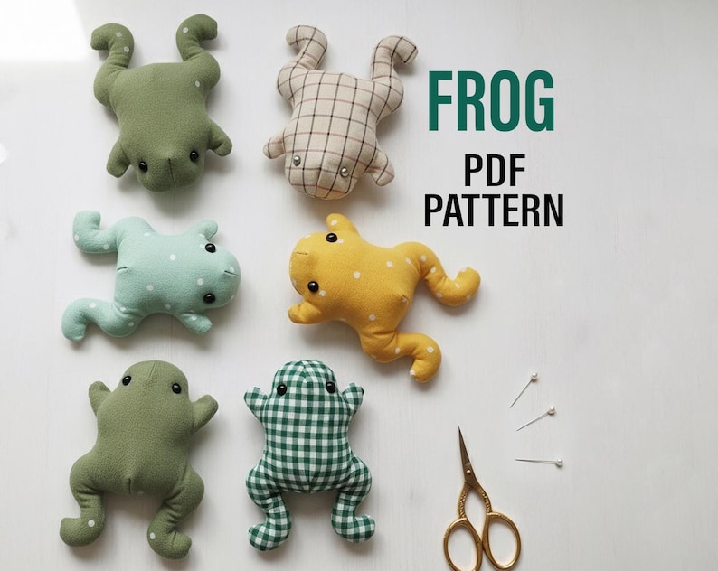 Peut inclure: Six jouets en forme de grenouille faits &agrave; la main, de diff&eacute;rentes couleurs et motifs, dont des motifs verts, jaunes et &agrave; carreaux. L'image comprend &eacute;galement le texte "FROG PDF PATTERN", des ciseaux dor&eacute;s et des &eacute;pingles.
