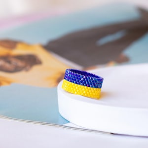 Könnte beinhalten: Ein gelber und blauer Perlenring, ein Symbol der ukrainischen Flagge.