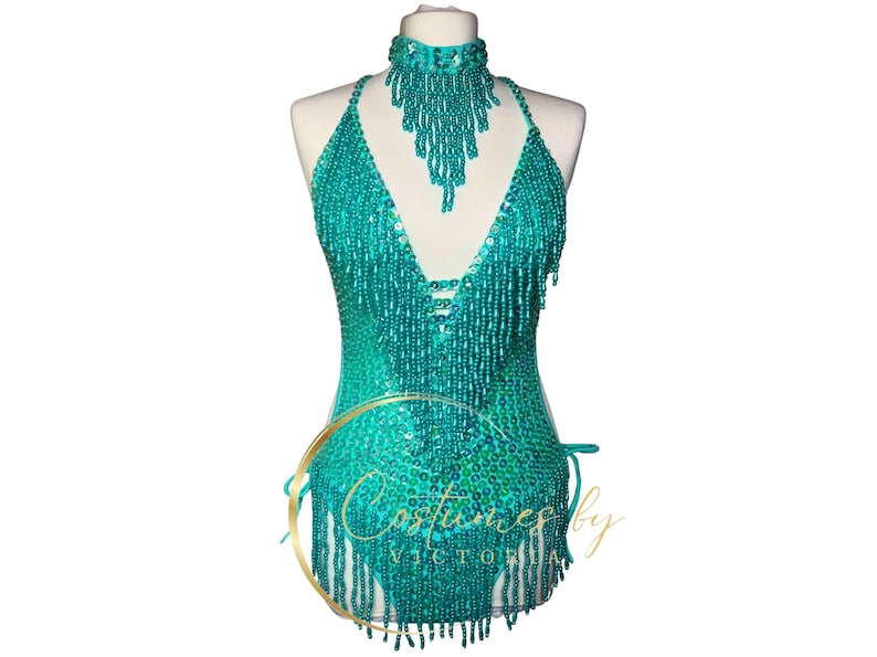 May include: Teal beaded halter top with fringe detail. The top has a V-neckline and is adorned with sequins. The top is tied at the back with a gold cord.