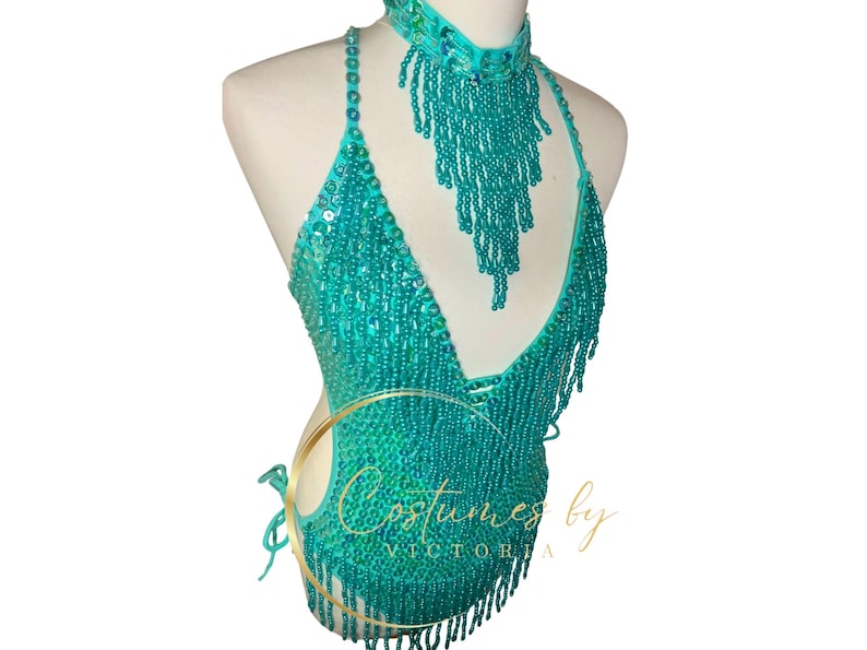 May include: Teal beaded halter top with fringe detail and matching beaded choker necklace. The top has a V-neckline and is made of sequins and beads. The choker is also made of sequins and beads and has a fringe detail. The top and choker are both very sparkly and glamorous.
