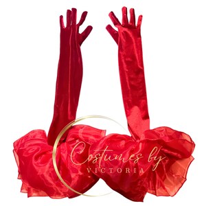 Pu&ograve; includere: Un paio di lunghi guanti di raso rosso con un tessuto di tulle rosso sullo sfondo. Il tessuto di tulle ha la scritta "Costumes by Victoria" stampata su di esso.