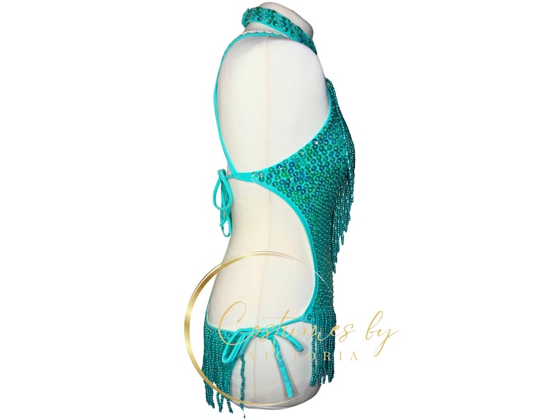 May include: A turquoise halter top with a beaded design and fringe. The top has a cutout back and is made of a stretchy fabric.