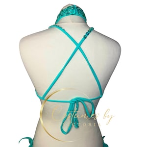 May include: A turquoise halter top with a criss-cross back and beaded straps. The top is tied at the back with a bow.