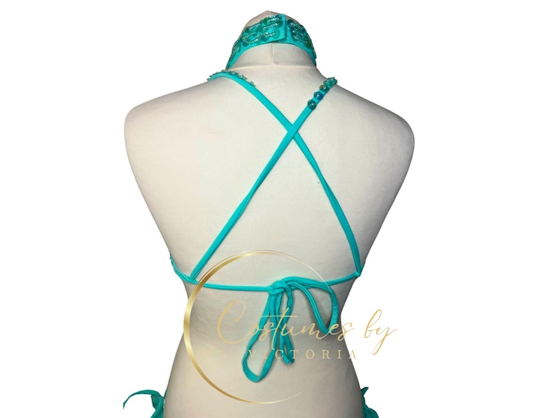 May include: A turquoise halter top with a criss-cross back and beaded straps. The top is tied at the back with a bow.