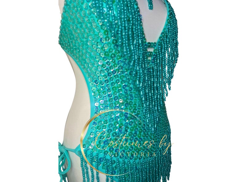 May include: A turquoise sequined and beaded halter top with fringe. The top has a cut-out design on the sides and a beaded fringe trim.