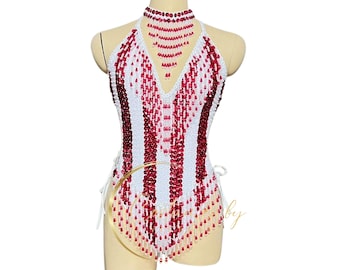 Può includere: Un top halter bianco e rosso con paillettes e un fondo a frangia. Il top ha una collana di perline con scollo a V.