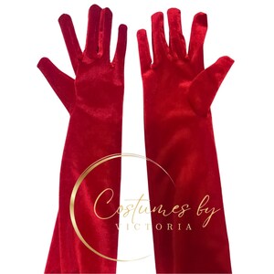 Pu&ograve; includere: Un paio di guanti lunghi in velluto rosso. I guanti sono completamente estesi e le dita sono distese.