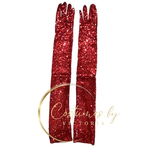 Op de afbeelding: Een paar lange, rode pailletten handschoenen. De handschoenen hebben een levendige rode kleur en zijn bedekt met glinsterende pailletten. De handschoenen zijn lang en reiken tot voorbij de elleboog. De tekst "Costumes by VICTORIA" staat in de afbeelding.
