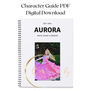 May include: A white spiral bound notebook with a gold circle around a photo of a woman dressed as Aurora from Sleeping Beauty. The notebook has the text "EST 1959 AURORA ONCE UPON A DREAM" printed on the front.