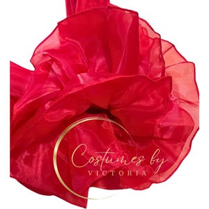 Pu&ograve; includere: Un tessuto di tulle rosso vivo con una texture arricciata. Il tessuto &egrave; raccolto in una forma circolare, creando un effetto voluminoso e drammatico. Il testo "Costumes by Victoria" &egrave; visibile al centro del tessuto.