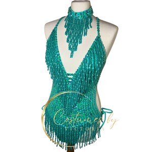 May include: A turquoise beaded halter top with fringe and a matching beaded choker. The top has a deep V-neckline and is made of sequins and beads.