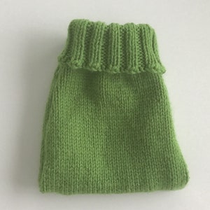 May include: A green knitted sweater for a small dog or cat. The sweater has a turtleneck collar and is made of a soft, comfortable material.