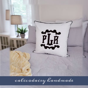 May include: White pillow with black embroidered monogram "PLR" in a decorative frame. The pillow has a black piping trim and is on a bed with a white and gray quilt.