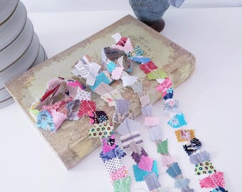 May include: Fabric snippet strips featuring a variety of colorful patterned textile scraps stitched together in long, decorative rows. The assorted fabric pieces include floral, polka dot, and geometric prints in pink, blue, green, and purple hues.