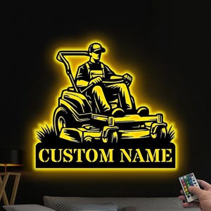 Op de afbeelding: Een geel verlicht silhouet van een persoon die een zitmaaier bedient met de tekst "CUSTOM NAME" eronder.