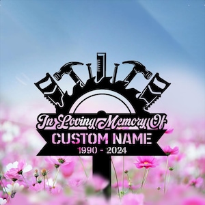 May include: Black metal memorial garden stake with carpentry tools and the text "In Loving Memory Of" above a banner for a custom name and dates 1990-2024. The design includes hammers, saws, nails, and a ruler.