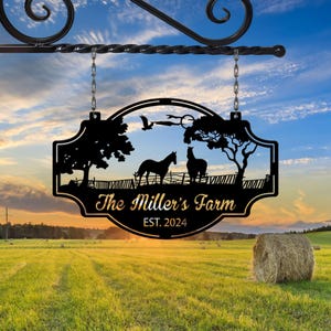 Puede incluir: Un letrero de metal negro con una silueta de dos caballos, árboles y un pájaro. El letrero dice "The Miller's Farm EST. 2024".