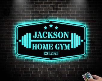 May include: A black and blue neon sign with the text "JACKSON HOME GYM EST. 2025" and a barbell graphic. The sign is illuminated with blue light and is mounted on a brick wall.