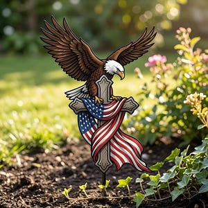 May include: A garden ornament depicting a bald eagle with outstretched wings, perched on a cross adorned with the American flag. The eagle has brown feathers, a white head, and a yellow beak. The cross is gray with red, white, and blue fabric.