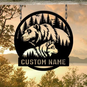 May include: Black metal sign featuring a bear and a wolf within a forest scene. The sign includes the text "CUSTOM NAME" on a rectangular banner. The sign is hanging from chains.