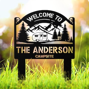 Puede incluir: Señal de bienvenida de metal negro con una silueta de caravana, montañas y árboles. El letrero dice "Bienvenido al camping The Anderson".