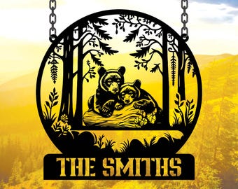 May include: Black metal silhouette of two bears cuddling on a log in a forest setting. The silhouette is attached to a chain and has a black metal nameplate below that reads "THE SMITHS".
