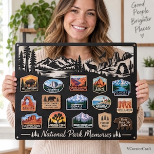 May include: A black metal display board featuring a laser-cut mountain and forest silhouette at the top. It includes fifteen colourful National Park patches and a bear-shaped plaque with the text "Parks Make Life Better" and "National Park Memories".
