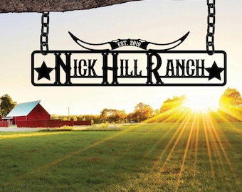 May include: Black metal sign with a white background that reads "Nick Hill Ranch" with a star on each side. The sign is hanging from a wooden branch with chains. The sign also has a metal cutout of a longhorn steer head with the text "Est. 2019" above the horns.