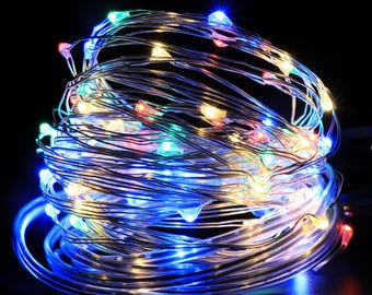 May include: A coiled string of multi-colored LED lights against a black background. The lights are a mix of blue, green, red, and yellow, creating a festive and decorative effect. The thin, flexible wire allows for versatile placement.