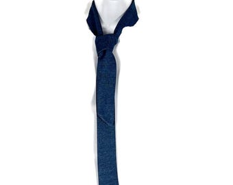 Könnte beinhalten: Eine dunkelblaue Jeans-Krawatte, am Hals geknotet, vor weißem Hintergrund. Die Krawatte hat eine einfarbige Farbe mit einer dezenten Textur, und der Knoten ist sauber gebunden. Die Form der Krawatte ist klassisch, geeignet für formelle oder lässige Kleidung.