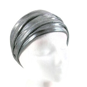 May include: A silver metallic headband with a turban-like style. The headband is made of a soft, stretchy fabric and is designed to be worn comfortably.