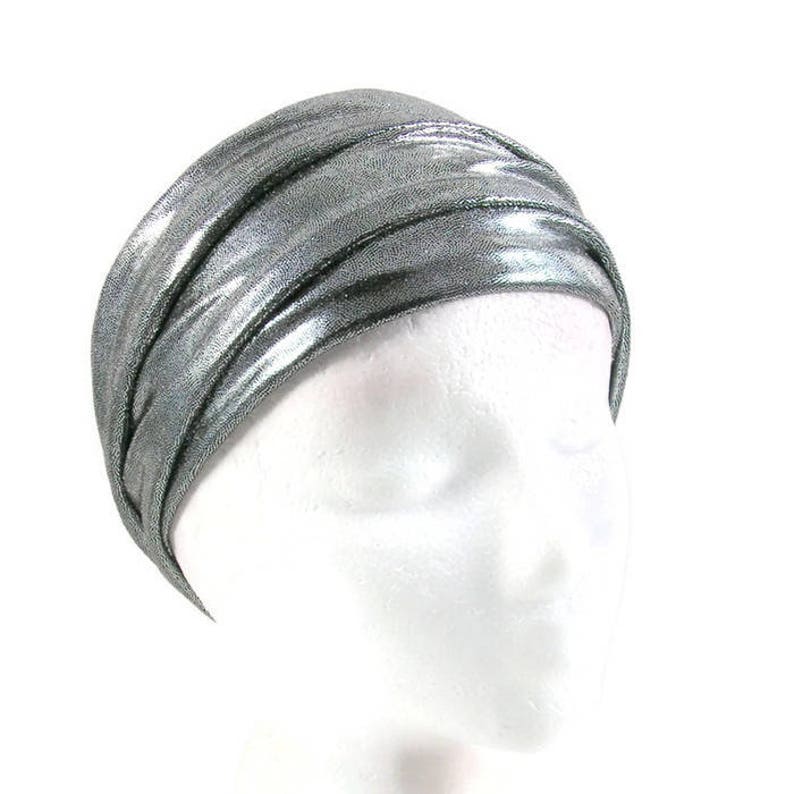 May include: A silver metallic headband with a turban-like style. The headband is made of a soft, stretchy fabric and is designed to be worn comfortably.