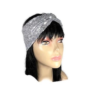 Può includere: Fascia turbante in paillettes argentate. La fascia è attorcigliata e annodata, creando un look elegante e alla moda.