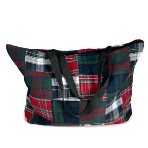 May include: A large patchwork tote bag made from different plaid fabrics in shades of red, green, black, and white. The bag has two black fabric handles.