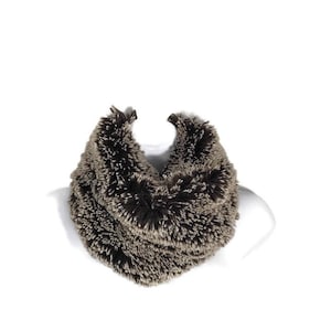 May include: A brown and beige faux fur infinity scarf. The scarf is soft and fluffy and would be a great addition to any winter wardrobe.