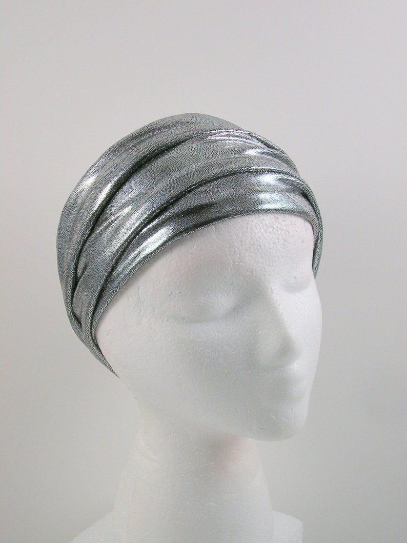 May include: A silver metallic headband with a crinkled texture. The headband is worn on a white mannequin head.