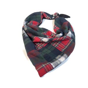 May include: A patchwork bandana in a classic plaid pattern. The fabric features a mix of red, green, navy, and white squares. The bandana is tied at the top with a black knot.