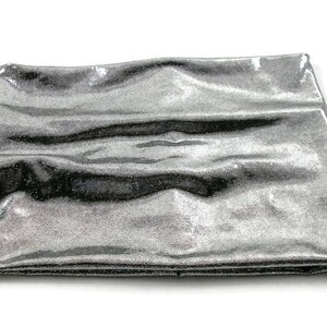 May include: A silver metallic fabric with a smooth, shiny texture. The fabric is folded and appears to be soft and flexible.