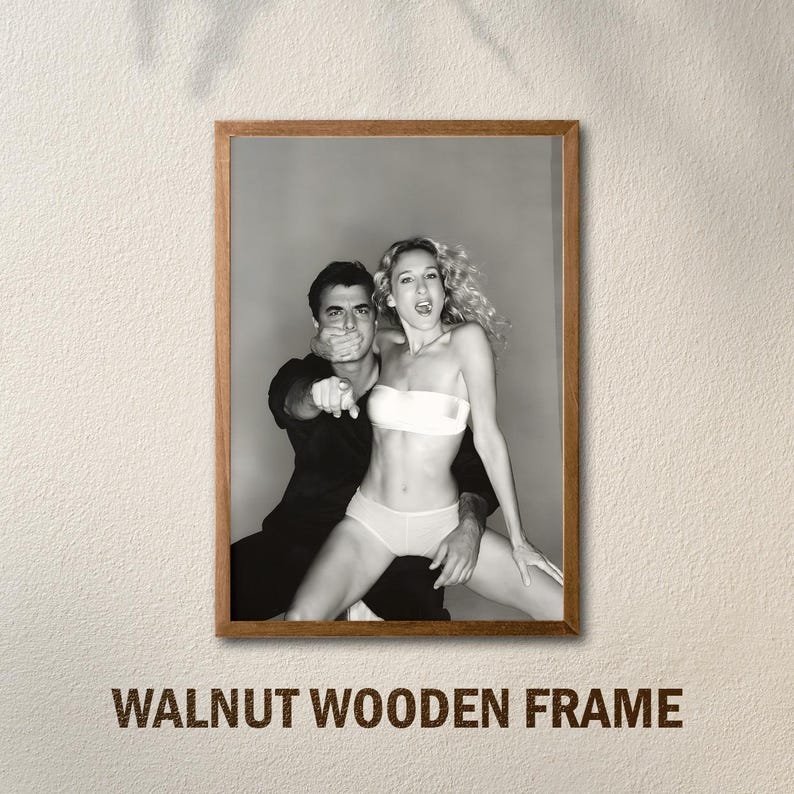 Peut inclure: Tirage encadr&eacute; en noir et blanc d'un homme et d'une femme dans une pose suggestive. La femme porte un haut et un bas blancs. L'homme pointe du doigt. Le cadre est en noyer. Le texte "WALNUT WOODEN FRAME" est en bas.