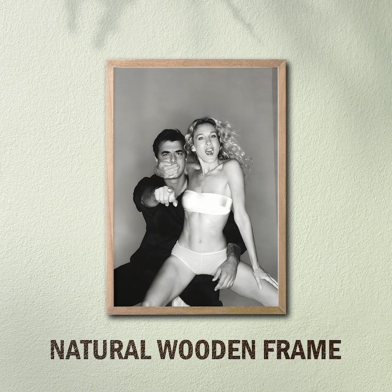 Peut inclure: Tirage encadr&eacute; en noir et blanc repr&eacute;sentant un homme et une femme. L'homme couvre la bouche de la femme et pointe. La femme porte un haut et un sous-v&ecirc;tement blancs. Le cadre est en bois naturel. Texte : "NATURAL WOODEN FRAME".