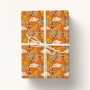 May include: Orange gift wrap with a white floral pattern. The wrap is tied with a white string bow.