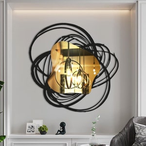 Peut inclure: Un miroir mural en métal noir avec une surface réfléchissante dorée. Le miroir a la forme d'un cercle avec un design abstrait en spirale. Le miroir est accroché à un mur blanc dans un salon moderne.