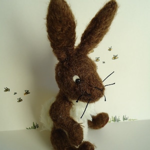 May include: A brown and white plush rabbit toy with long ears and a white belly. The rabbit is sitting on a white surface.